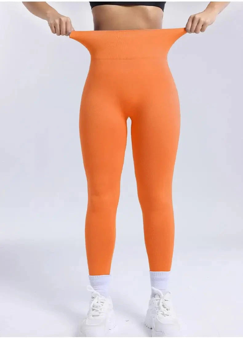 "High waist orange seamless leggings for women fitness, demonstrating stretchable waistband and snug fit ideal for gym and running."