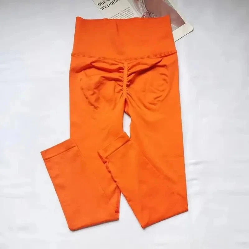 "Folded orange seamless leggings with ruched back design, highlighting high waist and push-up support for women’s fitness and yoga wear."