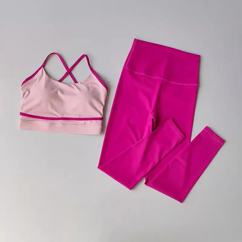 A two-piece activewear set featuring a light pink sports bra with magenta trim and matching high-waisted leggings in a vibrant magenta pink, laid flat on a light gray background.