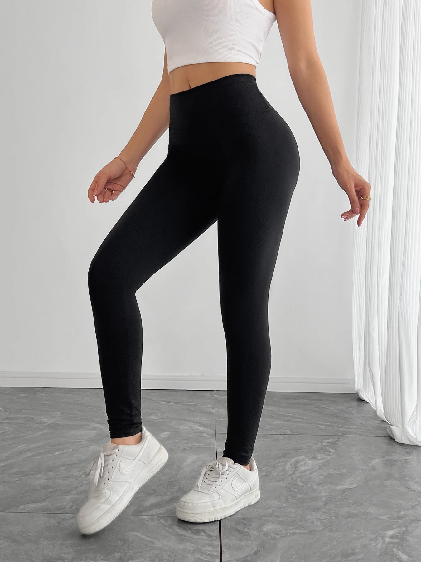 Person wearing black leggings and white sneakers on a plain background