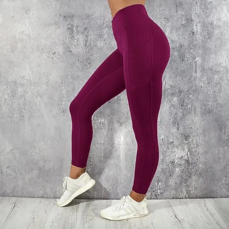 Person wearing maroon leggings and white sneakers against a gray concrete wall.